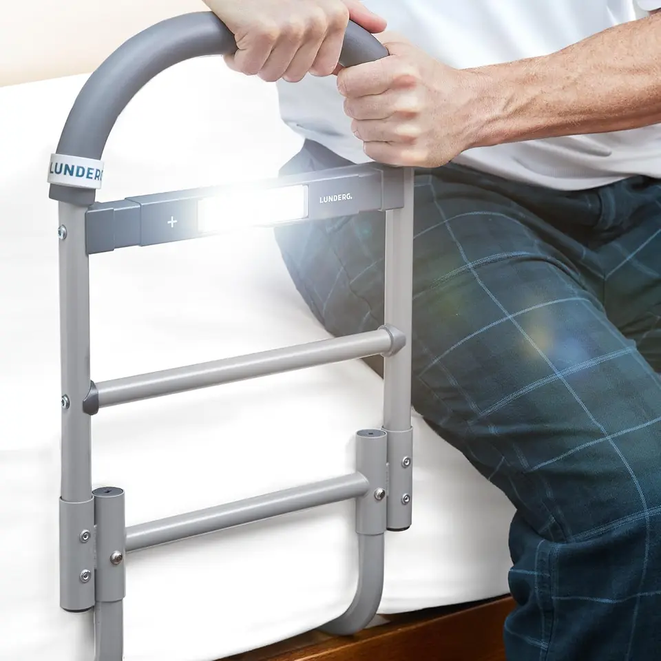 Hands gripping a bed rail handle with built-in motion light switched on
